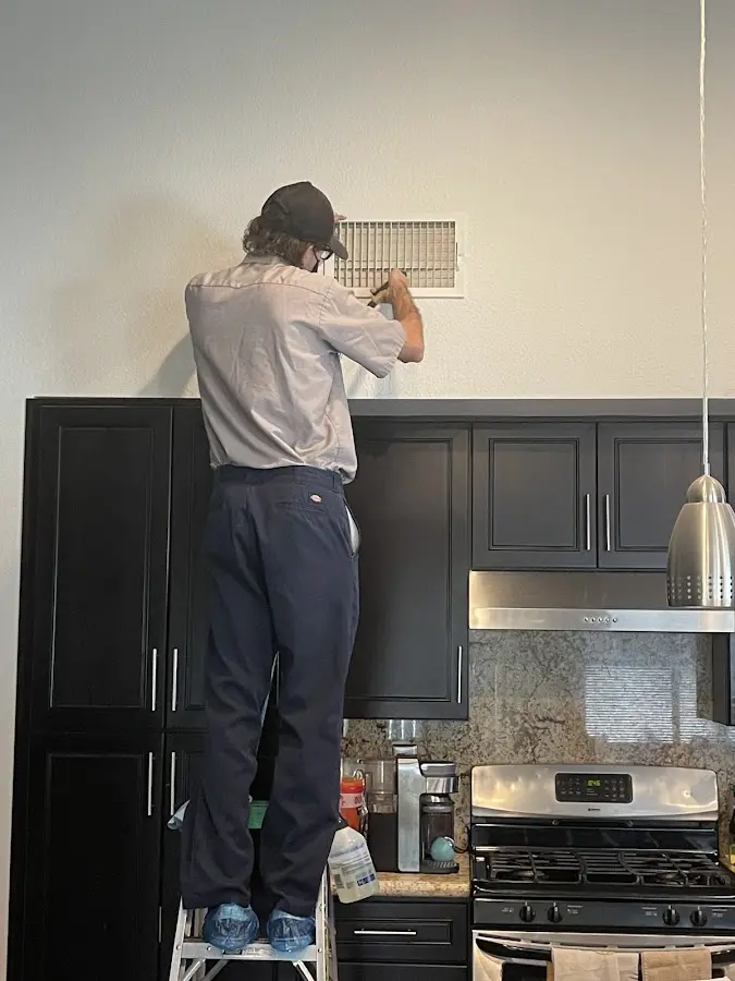 Technician inspecting an air vent during HVAC service in Kayenta